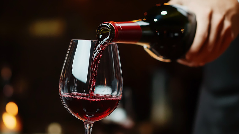 A glass of red wine being poured.