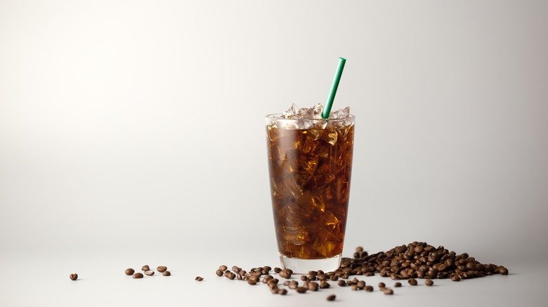 Coffee beans next to a glass of iced coffee