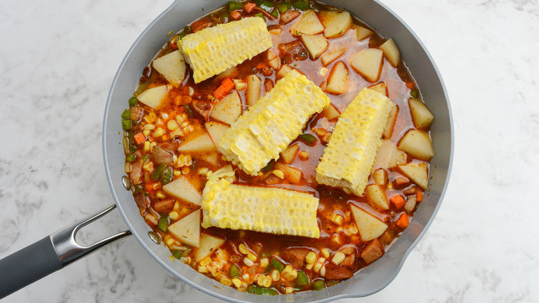 soup in pot with corn cobs