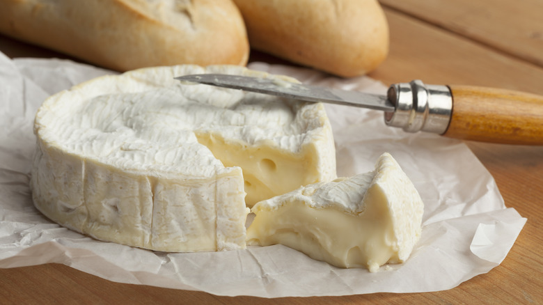 Wheel of Camembert with knife and baguettes