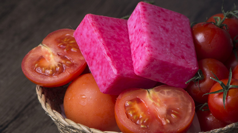 Two bars of pink soap on a bowl of tomatoes.
