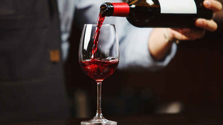A waiter pours red wine into a glass.