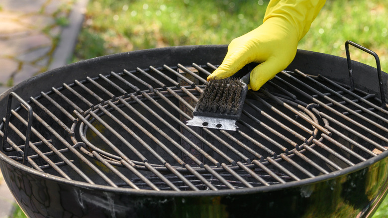 Hand cleaning a grill grate.