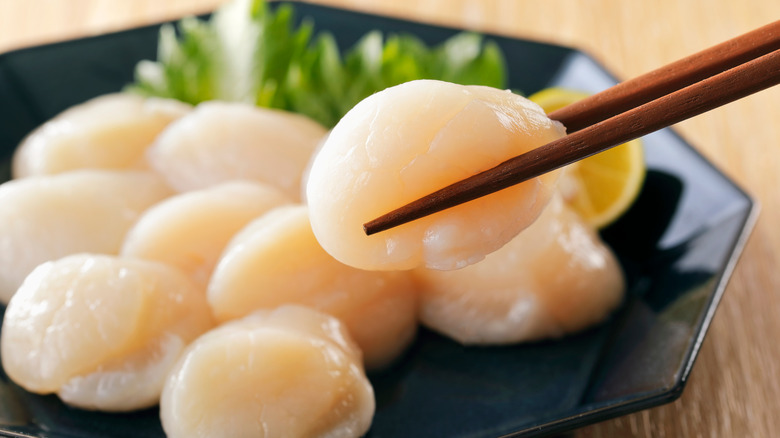 Raw scallop sashimi with chopsticks