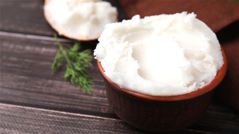 Cup of solidified beef tallow on wooden table