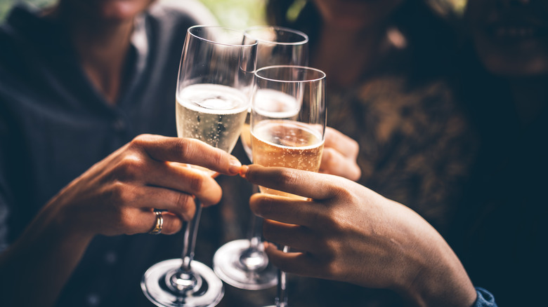 three people toasting with flutes of Champagne