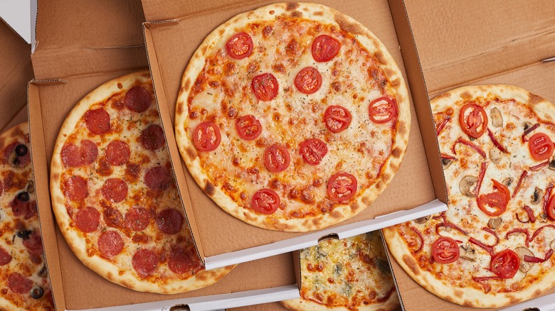 Various stacked pizzas in their boxes