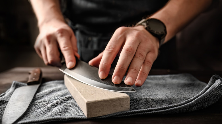 Man sharpening knife with a whetstone