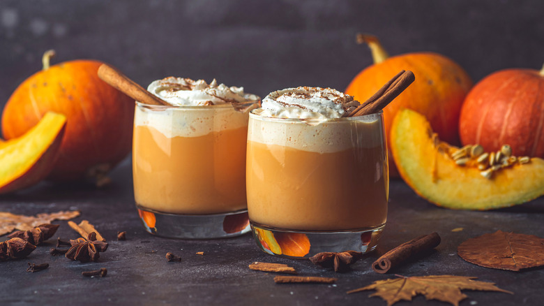 Two pumpkin chai lattes with whipped cream and cinnamon sticks