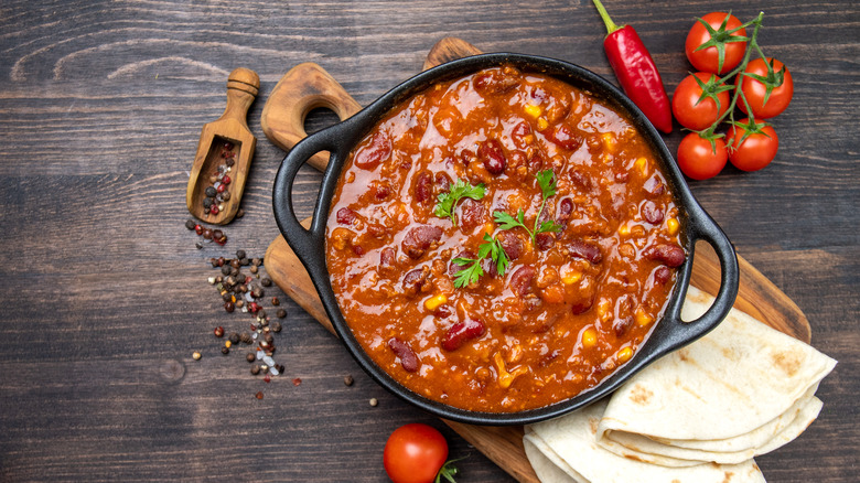 A pot of chili with kidney beans on a wooden table
