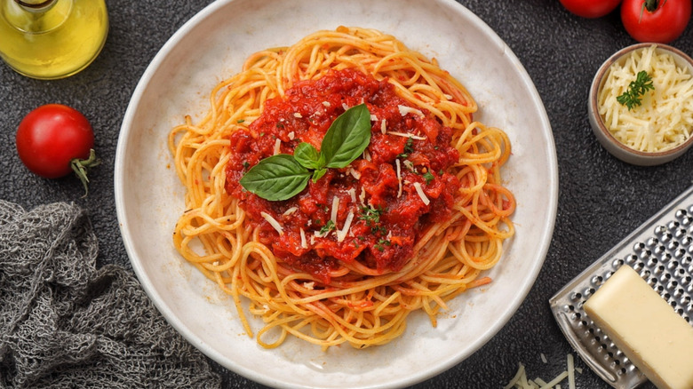 A plate of spaghetti with tomato pasta sauce and basil