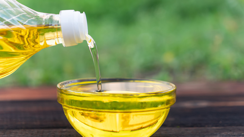 Canola oil being poured into a small glass container