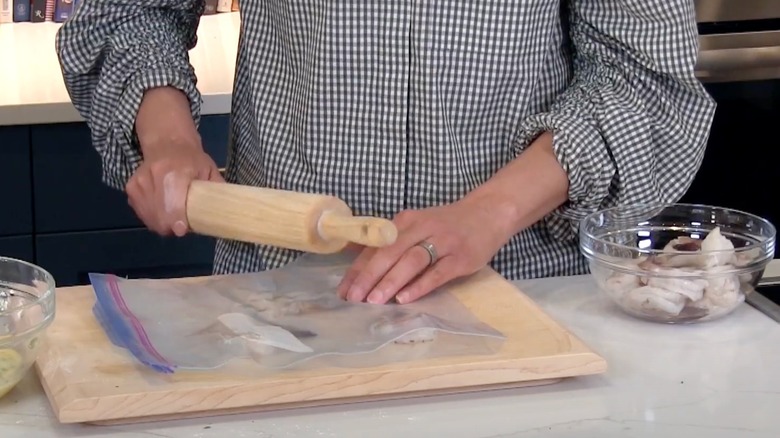 Carla Hall smashing raw shrimp with rolling pin