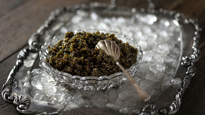 Black caviar in a bowl on a bed of ice with a silver spoon