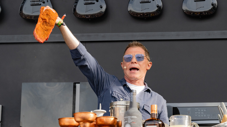 Chef Bobby Flay holds up a seasoned steak at a publicity event