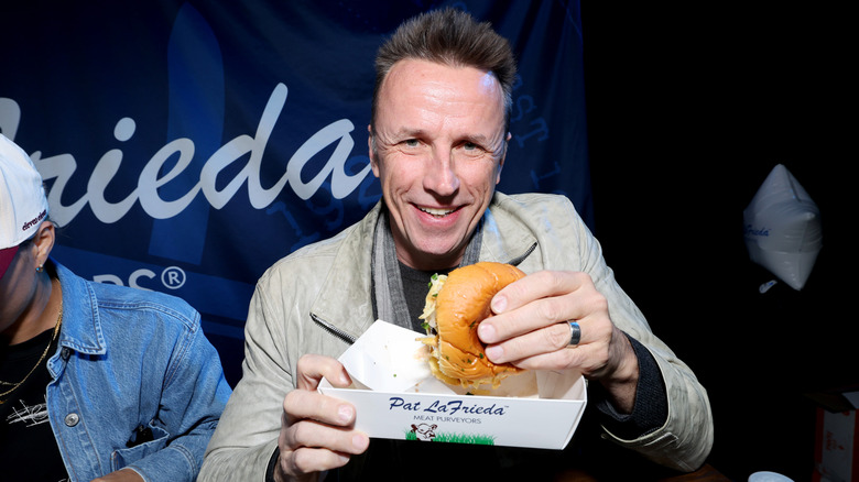 Chef Marc Murphy holds a hamburger at a press event