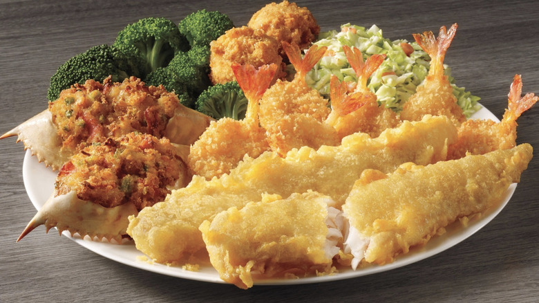 Captain D's Deluxe Seafood Platter with fried fish fillets, shrimp, stuffed crab, hushpuppies, broccoli, and greens.