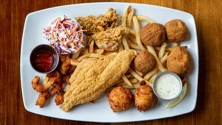Mixed seafood platter of fish, shrimp, fries, and hushpuppies.