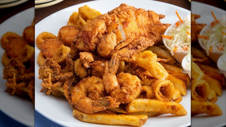 Legal Sea Foods Fisherman's Platter with fried fish, shrimp, calamari, and fries with a side of tartar sauce, coleslaw, and cocktail sauce.