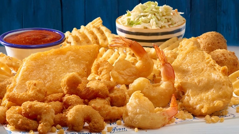 Long John Silver's Super Sampler Platter with fried fish, shrimp, popcorn shrimp, hushpuppies, and waffle fries with cocktail sauce and coleslaw on the side.