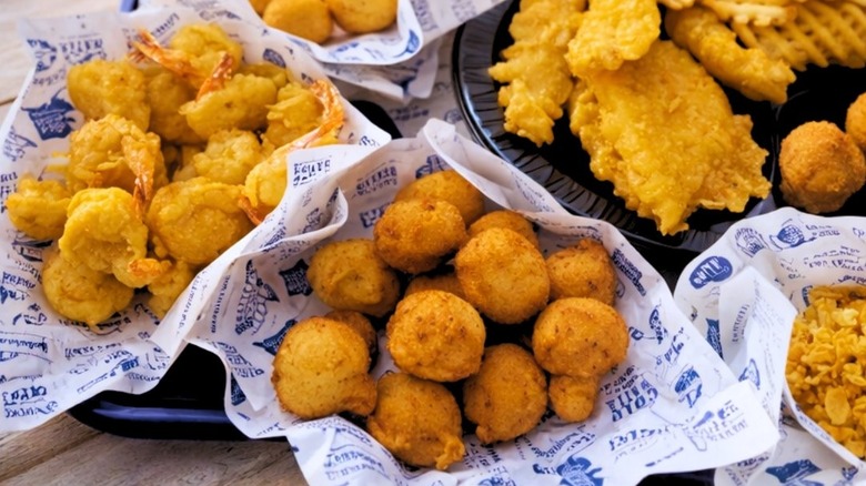 Hush puppies, fried shrimp, and fried fish sitting outside on a tray at Long John Silver's