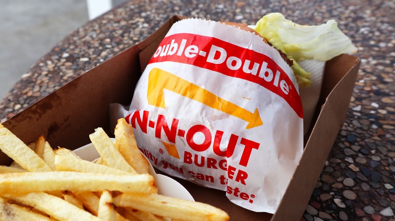A close up shot of a double double burger from In-N-Out next to an order of fries