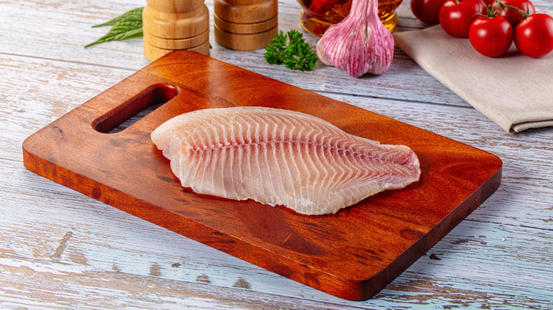 Raw tilapia fillet on cutting board