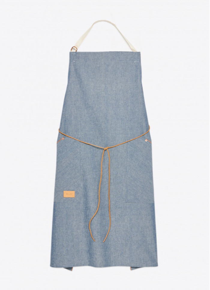 The apron was designed with lightweight orange line selvedge denim, deep pockets accented with copper rivets, a leather tie, and adjustable neck strap. (Photo credit: Billy Reid)