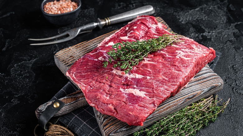 raw brisket with rosemary on black table