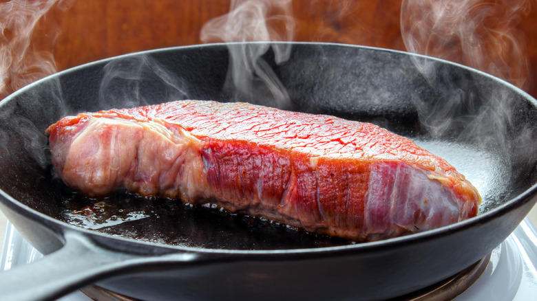 brisket being seared in a large saute pan