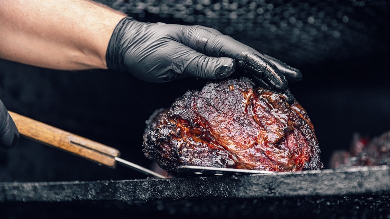 pitmaster handling brisket in smoker