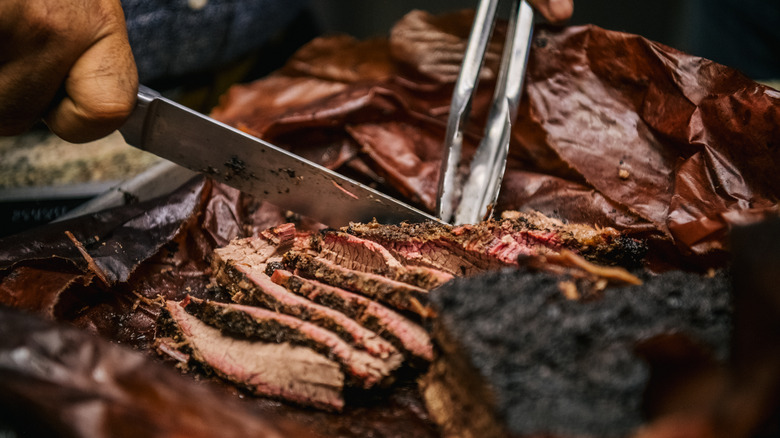 smoked barbecue being sliced on cutting board