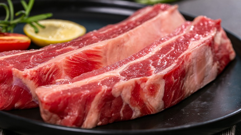 slices of raw brisket on a black plate