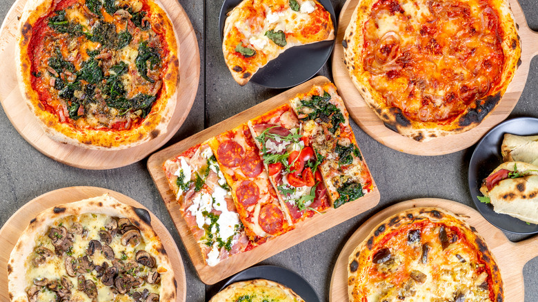 Various styles of pizzas on wooden boards.