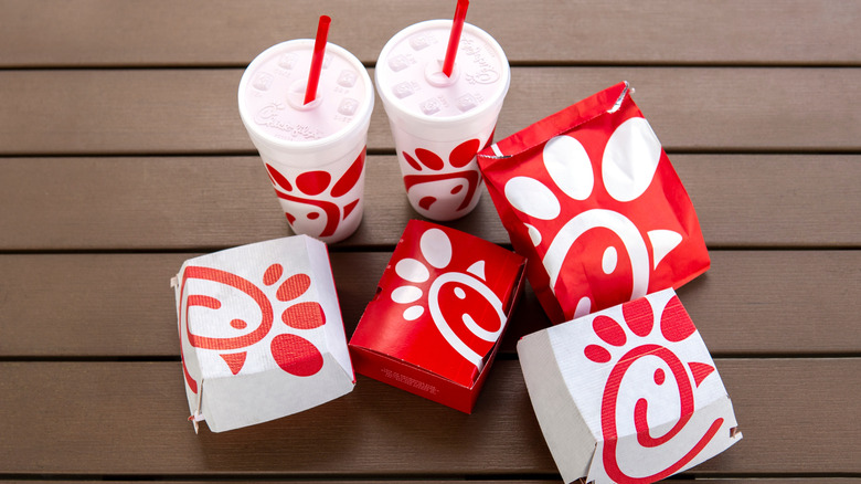 Generic Chick-fil-A food in boxes with sodas beside them on a picnic table.