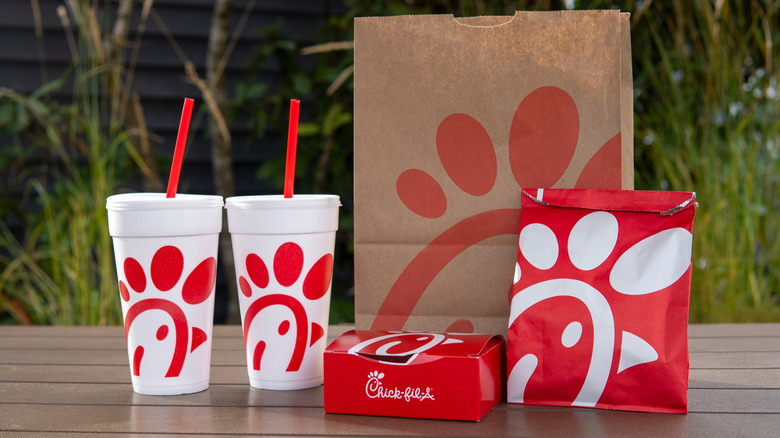 Chick-fil-A bags, containers, and drinks on a wooden table outside