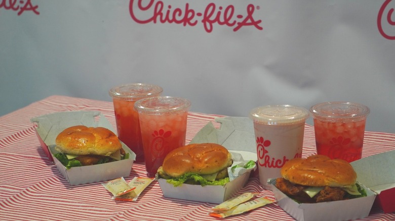 Side angle of Chick-fil-A Jalapeño Club Chicken Sandwiches, Jalapeño Ranch sauce packets, and Strawberry Hibiscus Beverages.