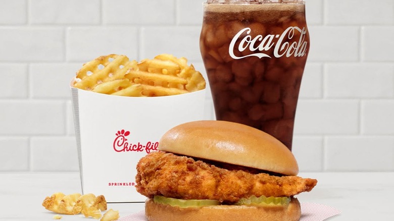 A chicken sandwich meal with waffle fries and a glass of Coca-Cola