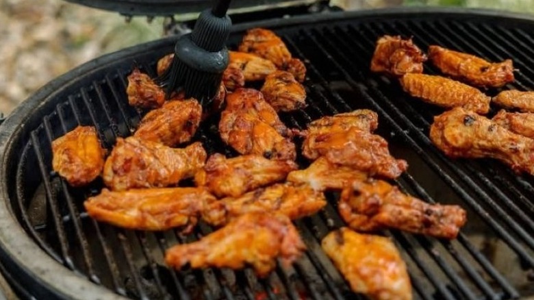 Chicken wings lie on the grates of an outdoor grill
