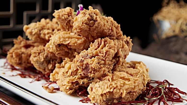 Fried chicken wings lie on a white plate with garnishes