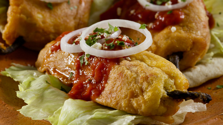 Chiles rellenos with onion rings and salsa on top