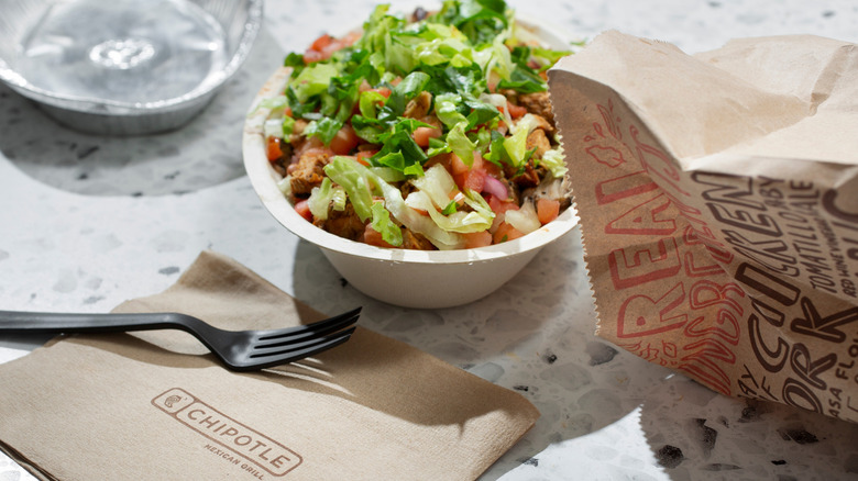 A Chipotle bowl with bag and napkins.