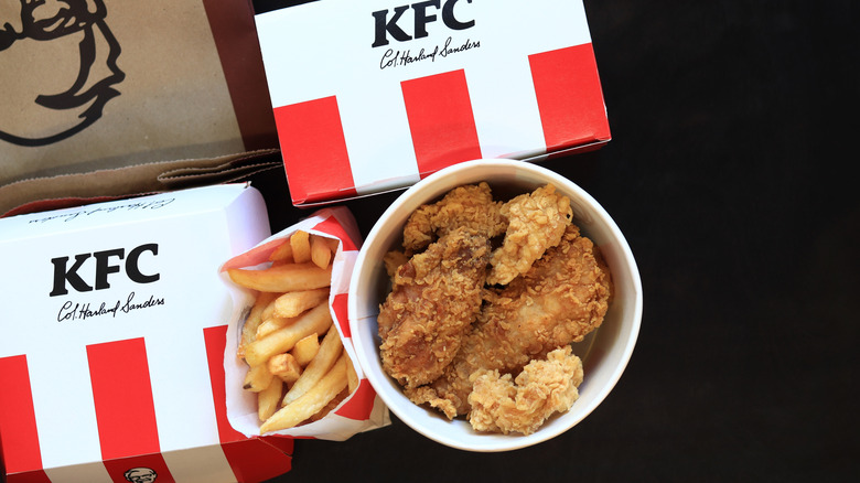 KFC wings, fries, and boxes over black background
