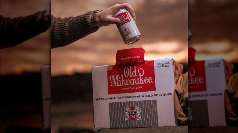 Hand pulling can of Old Milwaukee from case