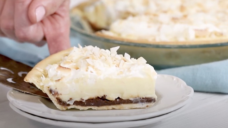 Black bottom pie slice topped with coconut flakes dished onto a white plate