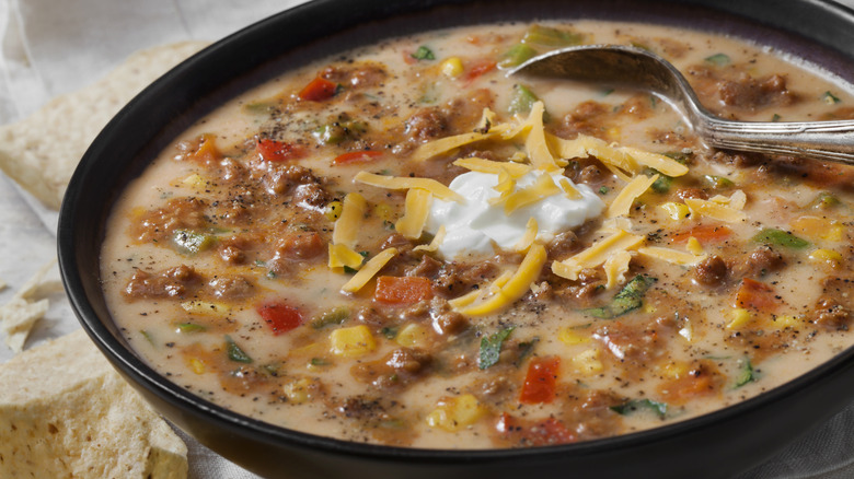 taco soup in a bowl with sour cream and shredded cheese