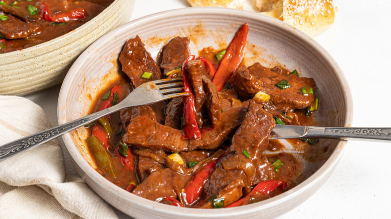 Plate with a pepper steak with for and knife inside.