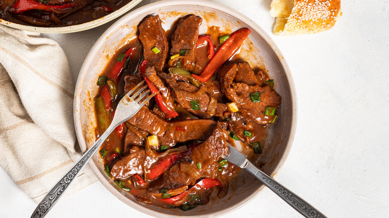 Overhead shot of a plate with pepper steak and a fork and knife inside
