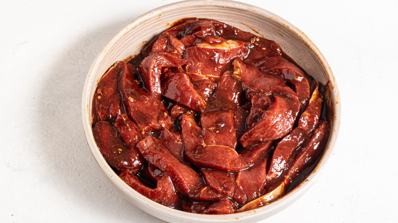 Bowl with slices of meat marinated in a brown sauce