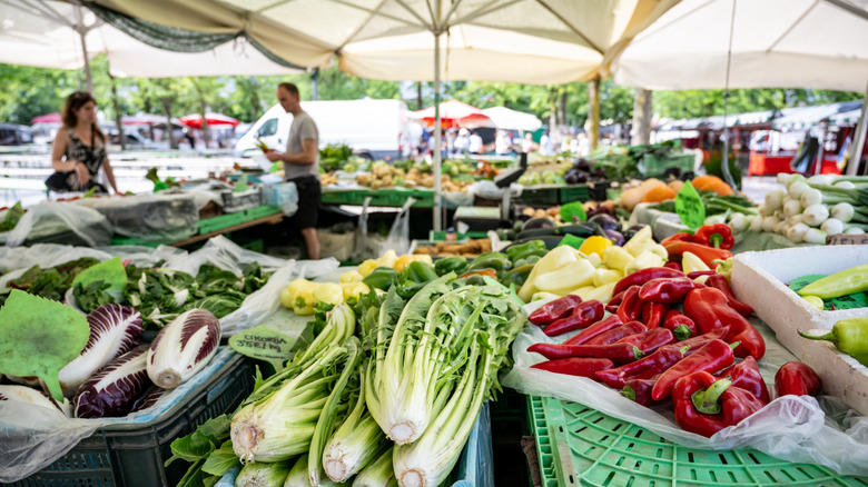 Produce stand full of various leafy greens and veggies at a farmer's market